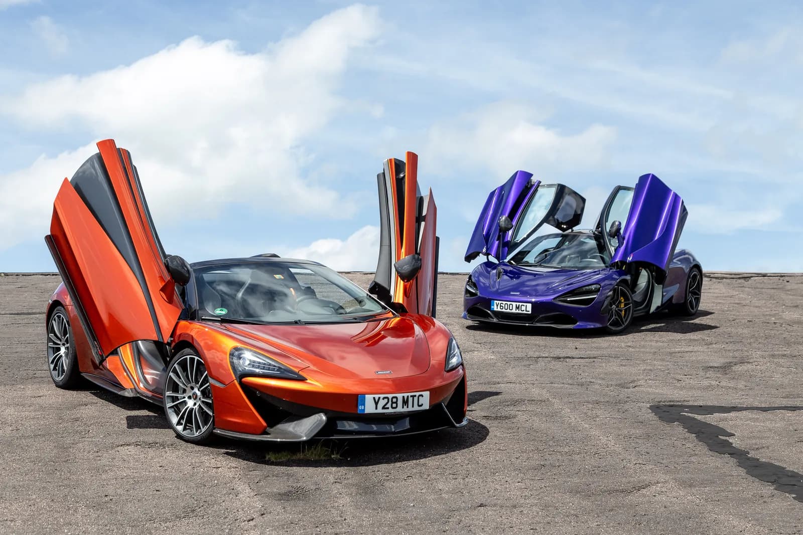 McLaren 570S Spider and 720S supercars with doors open under a clear sky